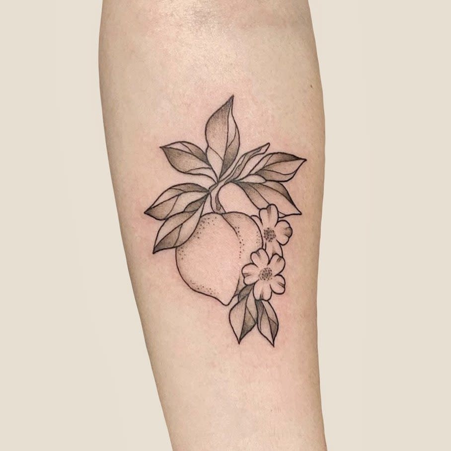 Tattoo of a peach with leaves and two flowers on an arm